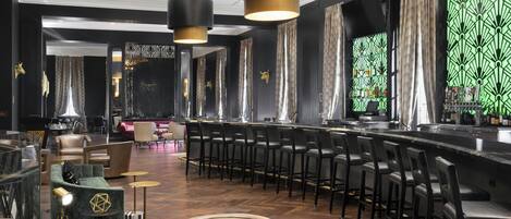 A modern bar area with leather chairs, a bar counter, and pendant lighting.