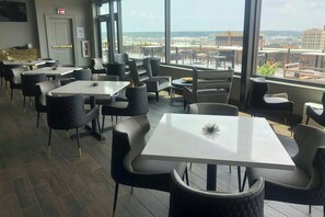 A restaurant with tables and chairs, large windows, and a view of the city. - The Warrior Hotel, Autograph Collection (Sioux City)