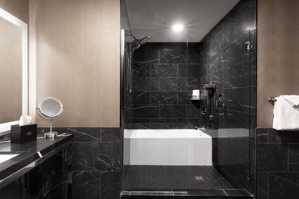 A modern bathroom with a glass-enclosed shower, a standalone bathtub, and a vanity with a mirror.