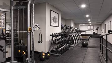 Une salle de sport équipée de matériel d’exercice, de tapis de course et de supports pour les poids.