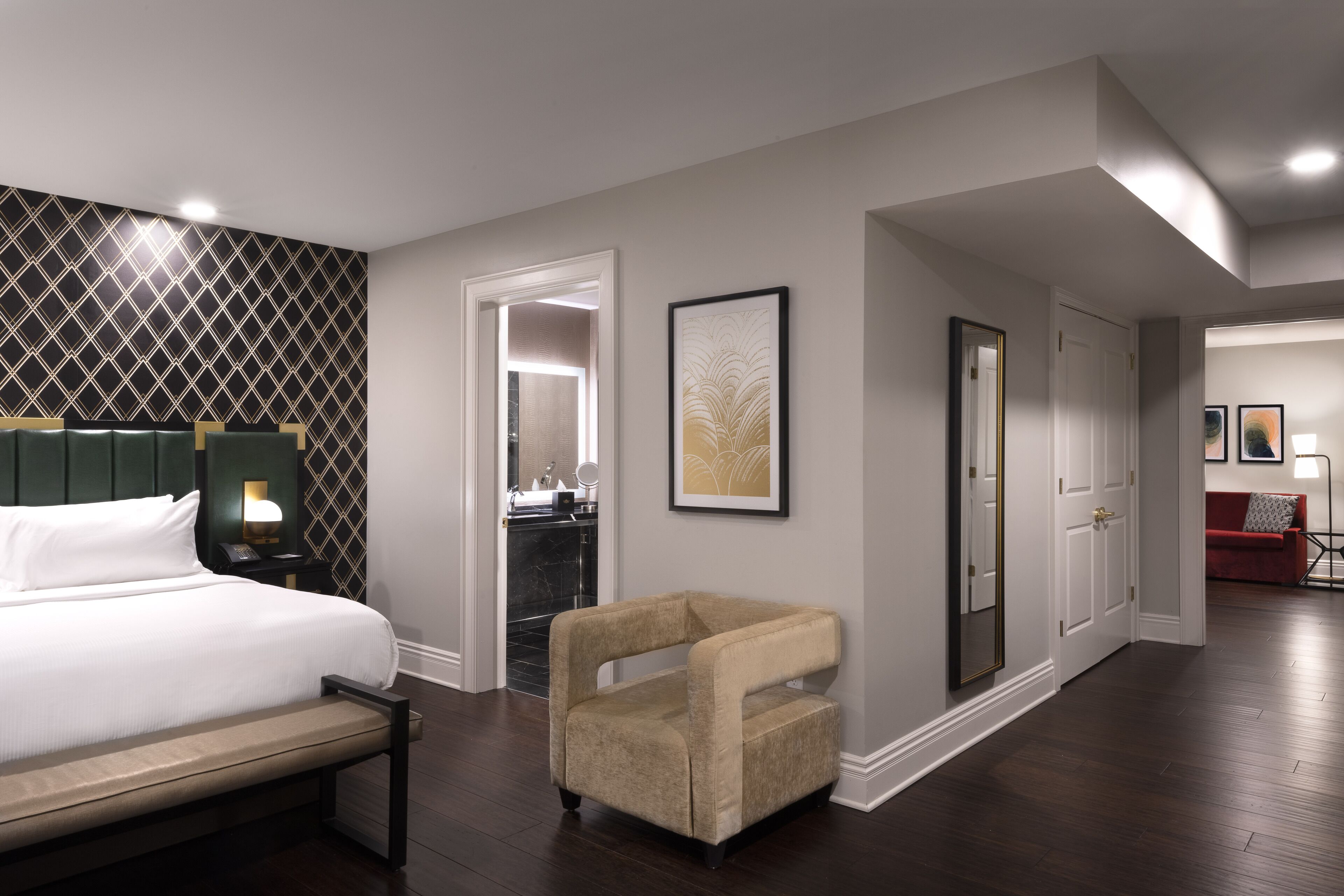 Une chambre d’hôtel comprenant un lit, une chaise, un bureau, un miroir et une porte donnant sur une salle de bain.