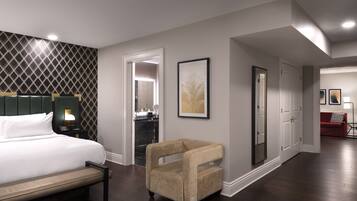 Une chambre d’hôtel comprenant un lit, une chaise, un bureau, un miroir et une porte donnant sur une salle de bain.