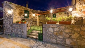 A stone-walled building with a green door, potted plants, and a metal gate. - Villa Holiday Coral (Vinodol)