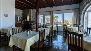 Un restaurante con mesas cubiertas con manteles blancos, sillas de madera y una pared de piedra.