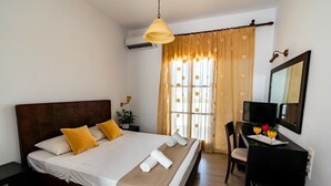 Una habitación de hotel con una cama grande, un escritorio con televisor y un espejo.
