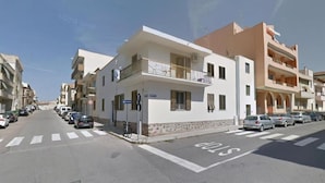 Vista de la calle con una fila de coches estacionados, una señal de parada y edificios de varios pisos con balcones.