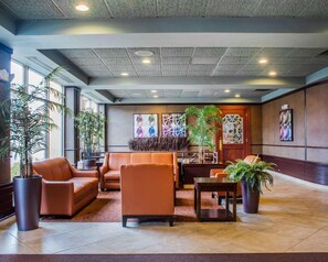 A lobby with leather seating, potted plants, and artwork on the walls. - Quality Inn & Suites Riverfront (Oswego)