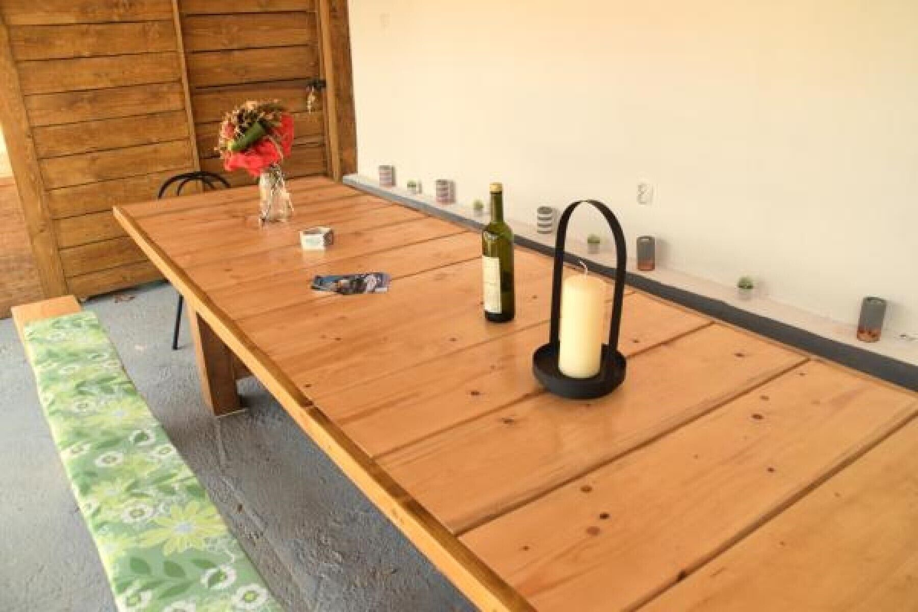 Une table en bois, un chandelier, une bouteille de vin et un vase rempli de fleurs.