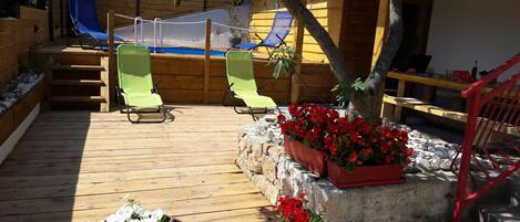 A wooden deck with outdoor seating, a rope swing, and potted plants.