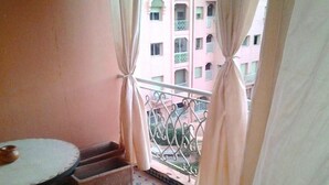 Varanda com mesa e degraus, com vista para um edifício com varandas.