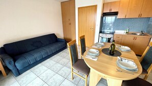 Un espace de vie compact comprenant un coin repas, un canapé et une kitchenette.