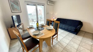Un coin repas avec une table ronde, des chaises et un téléviseur placé dans un angle.