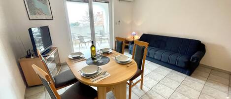 A dining area with a round table, chairs, and a television in the corner.