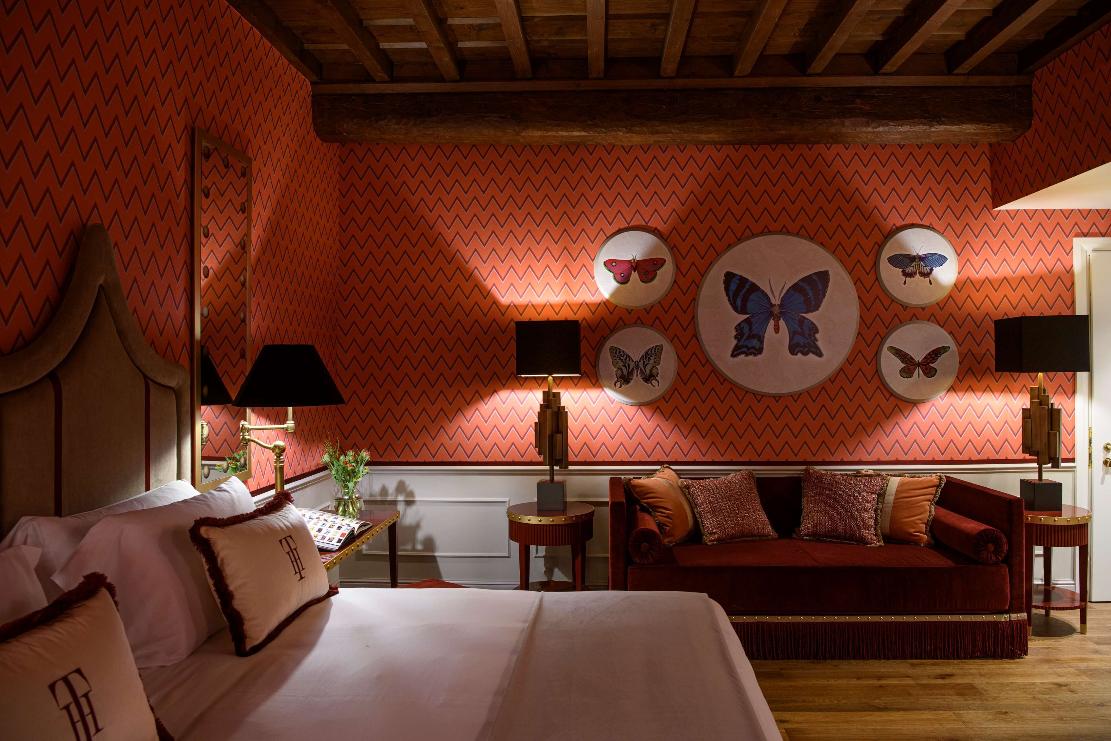 Une chambre avec un lit, un canapé rouge et des décorations murales représentant des papillons.