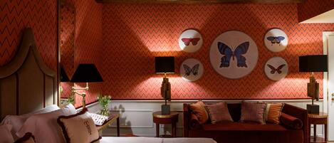 Une chambre avec un lit, un canapé rouge et des décorations murales représentant des papillons.