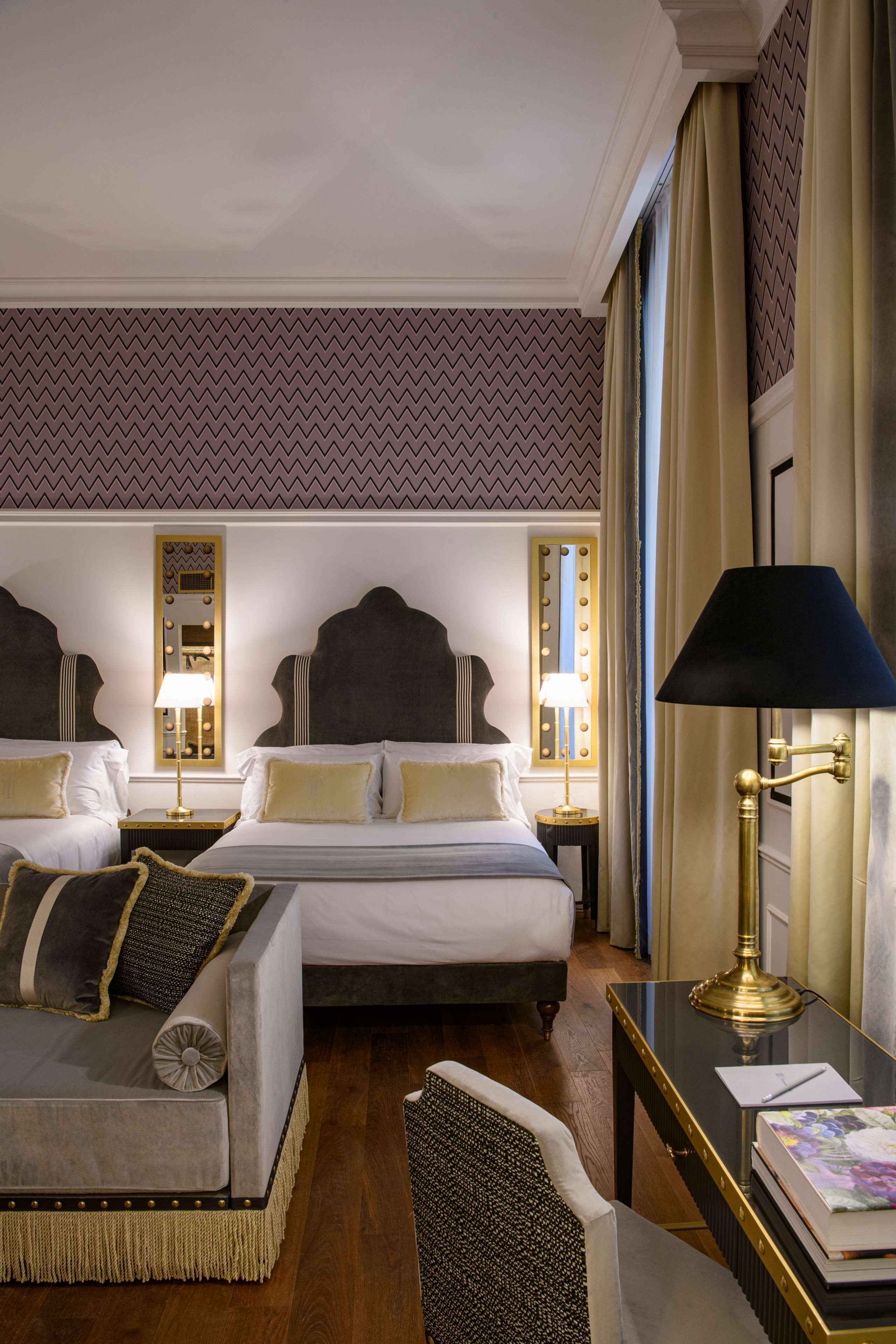 Une chambre d’hôtel avec deux lits, un bureau, une chaise et une lampe.