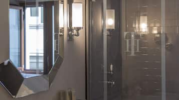Une salle de bain moderne avec un grand miroir, un lavabo, une douche et un espace douche fermé par des parois de verre.