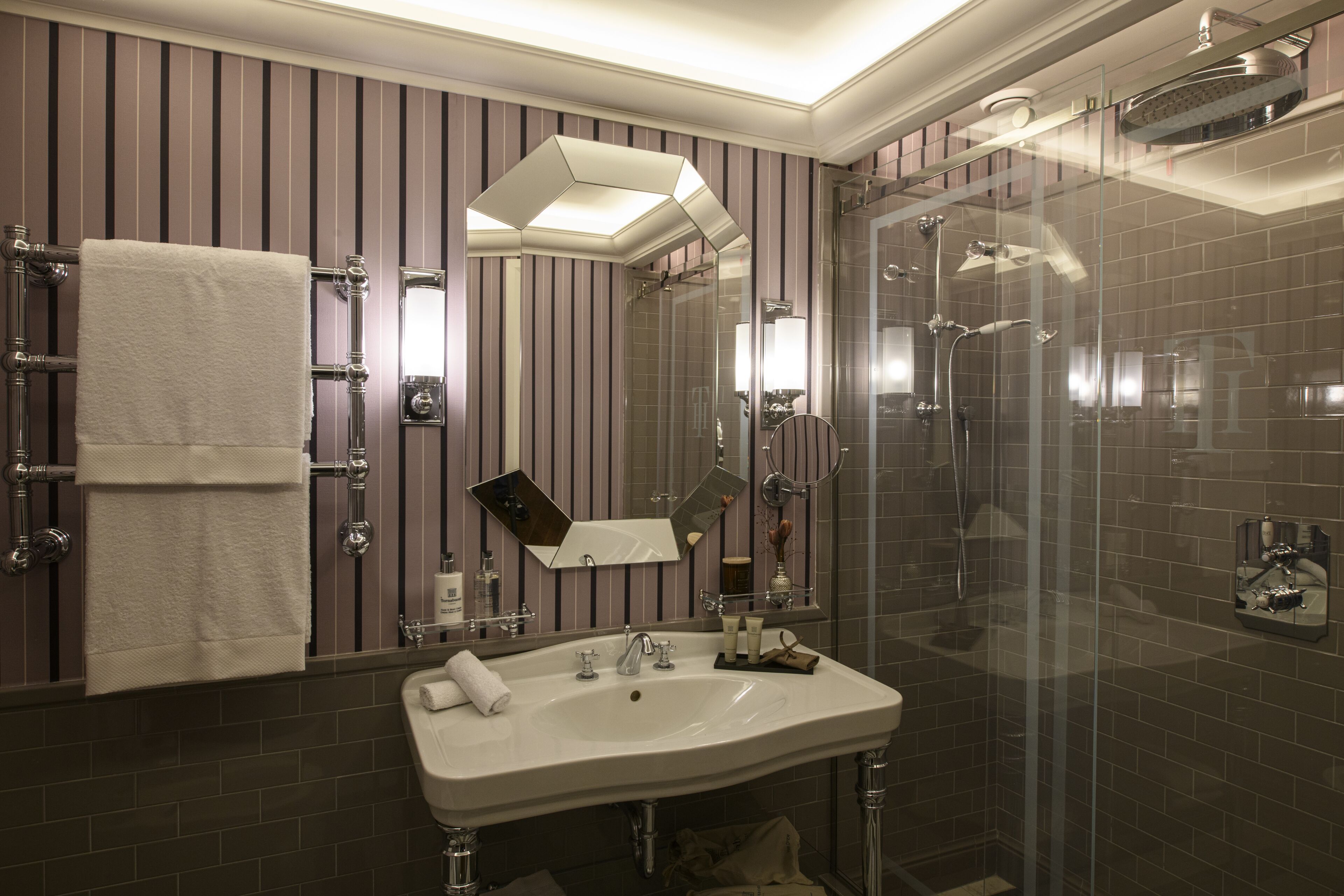 A modern bathroom with a large mirror, a sink, and a glass-enclosed shower.