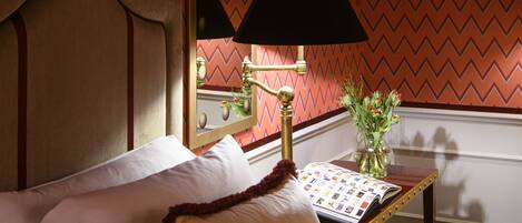 A hotel room with a bed, a bedside table with a lamp, and a mirror on the wall.