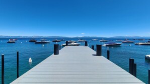 A pier leading into a calm body of water with several boats docked at the end.