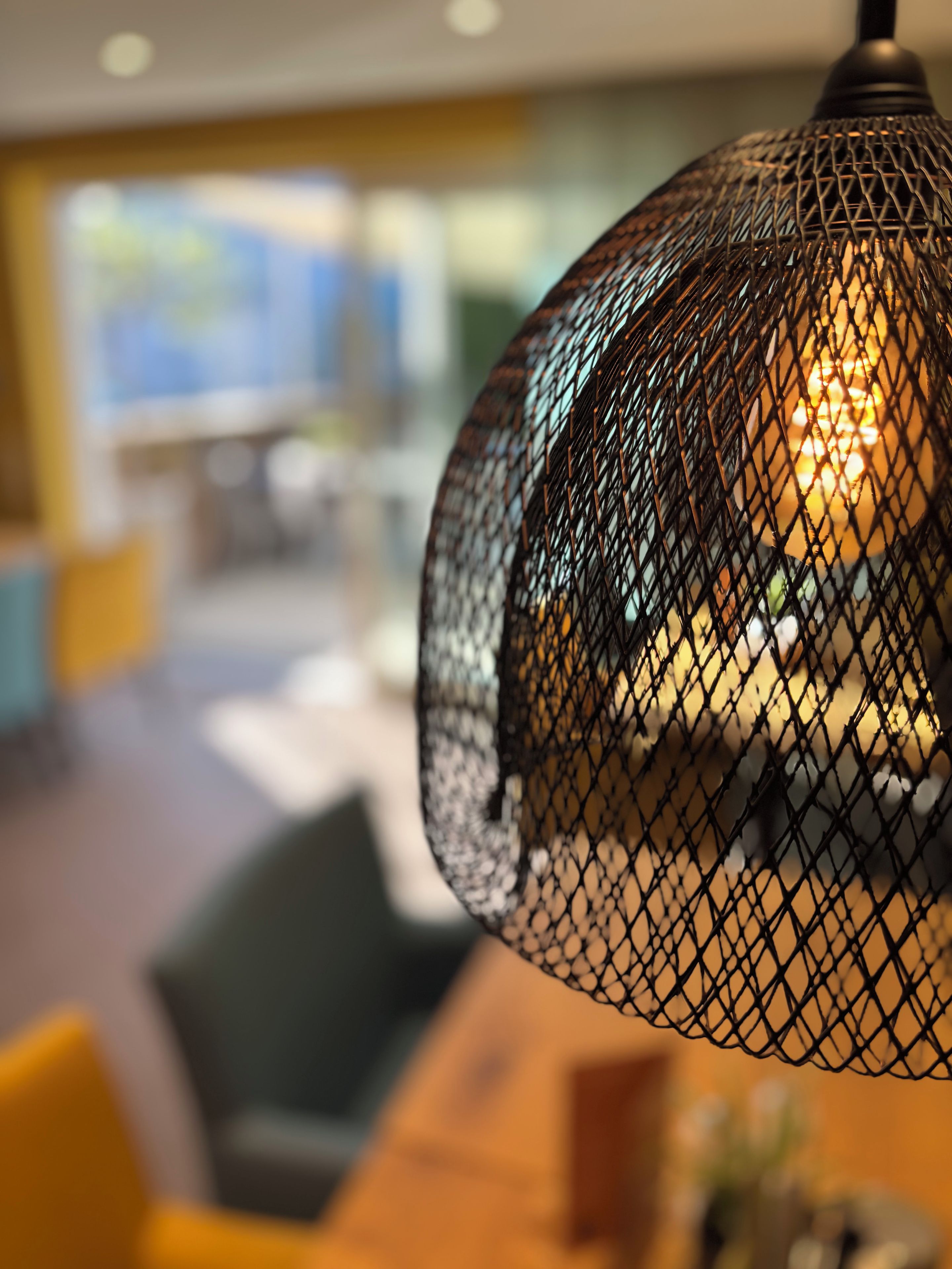 Primer plano de una lámpara colgante esférica con textura y una cálida fuente de luz en su interior.
