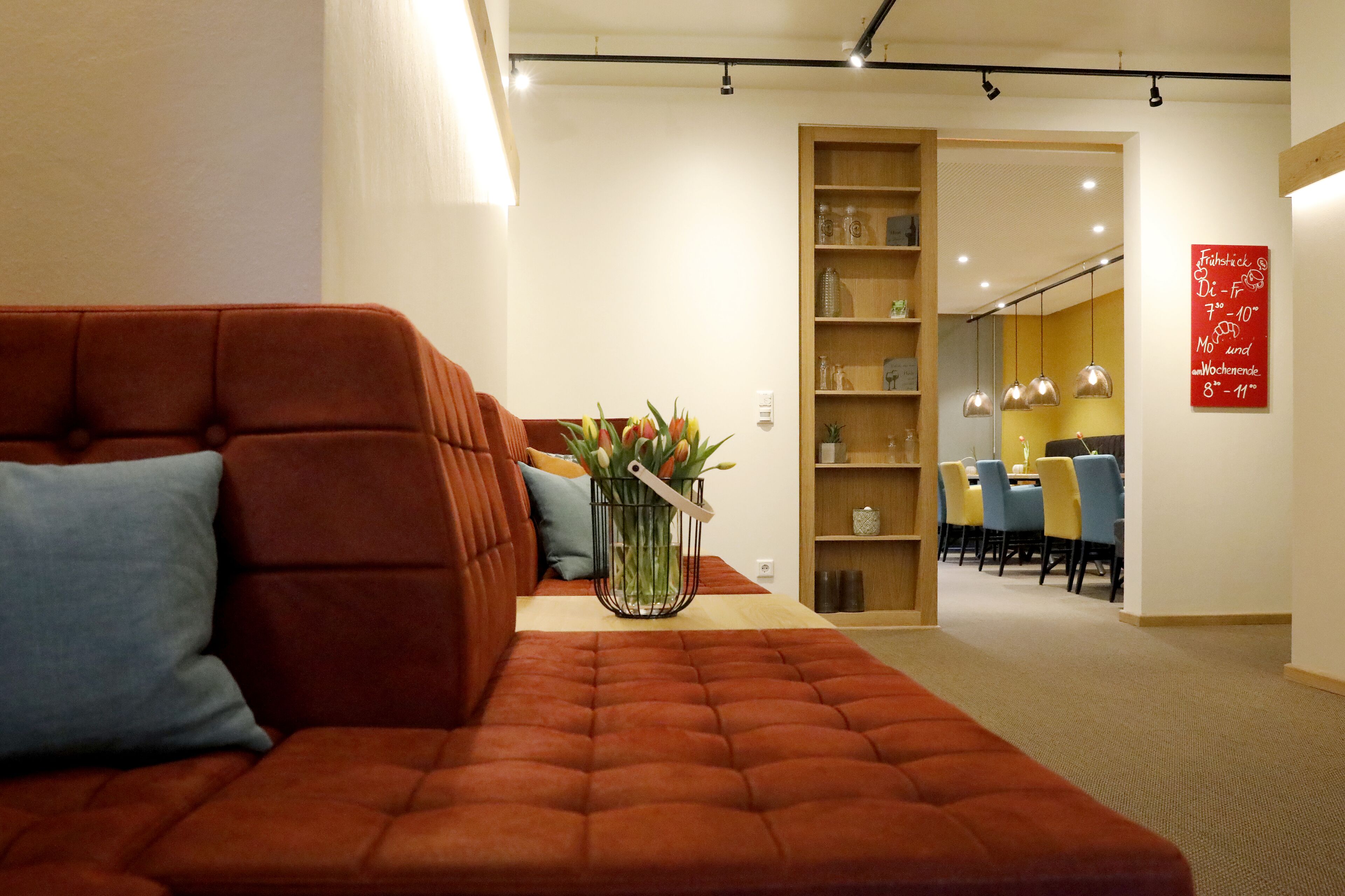 A modern living room with a red sofa, a coffee table, and a bookshelf.