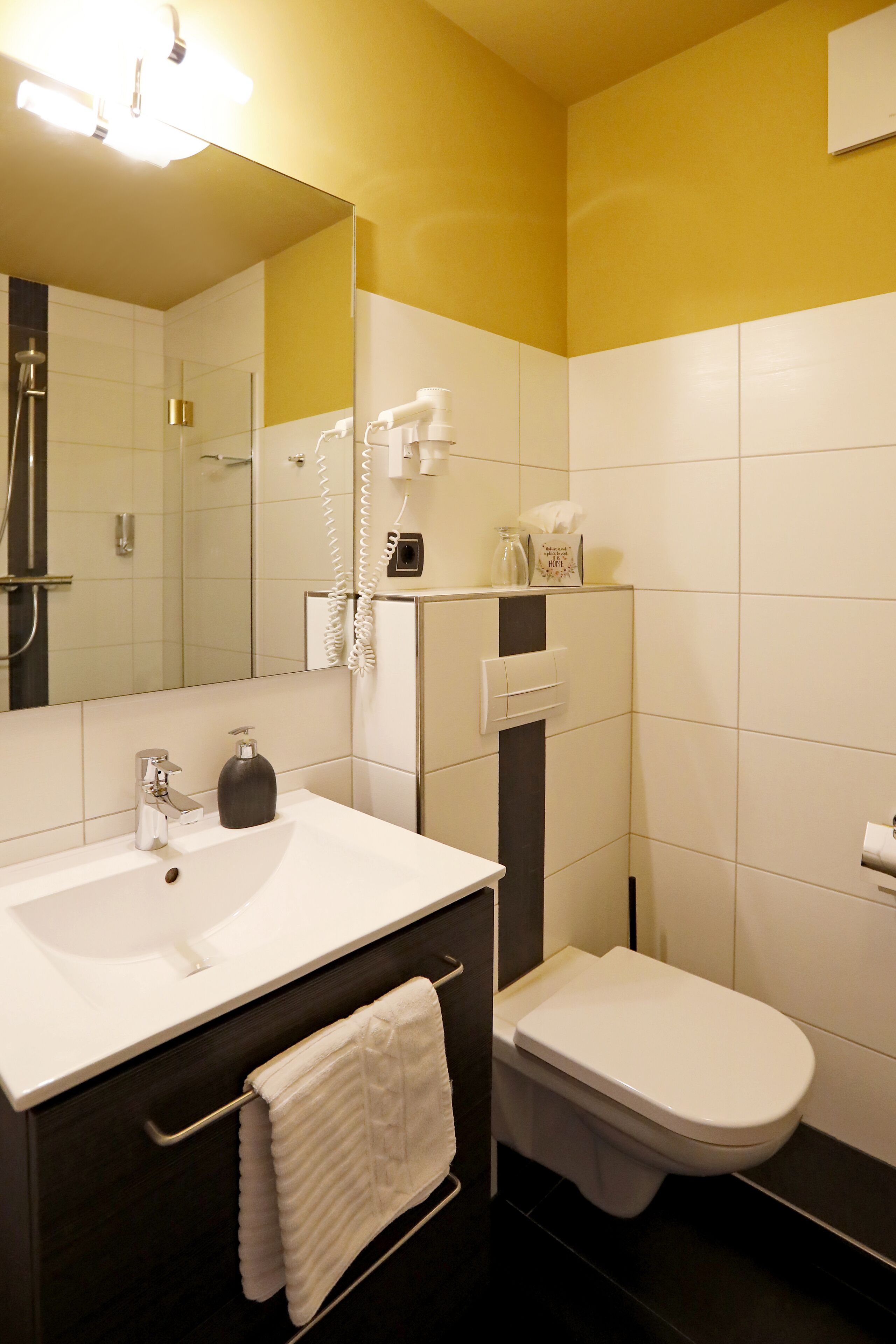 A modern bathroom with a white sink, a toilet, and a mirror.