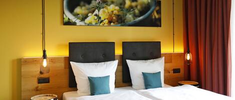 A double bed with white and teal pillows, a wooden headboard, and a wooden barrel beside it.