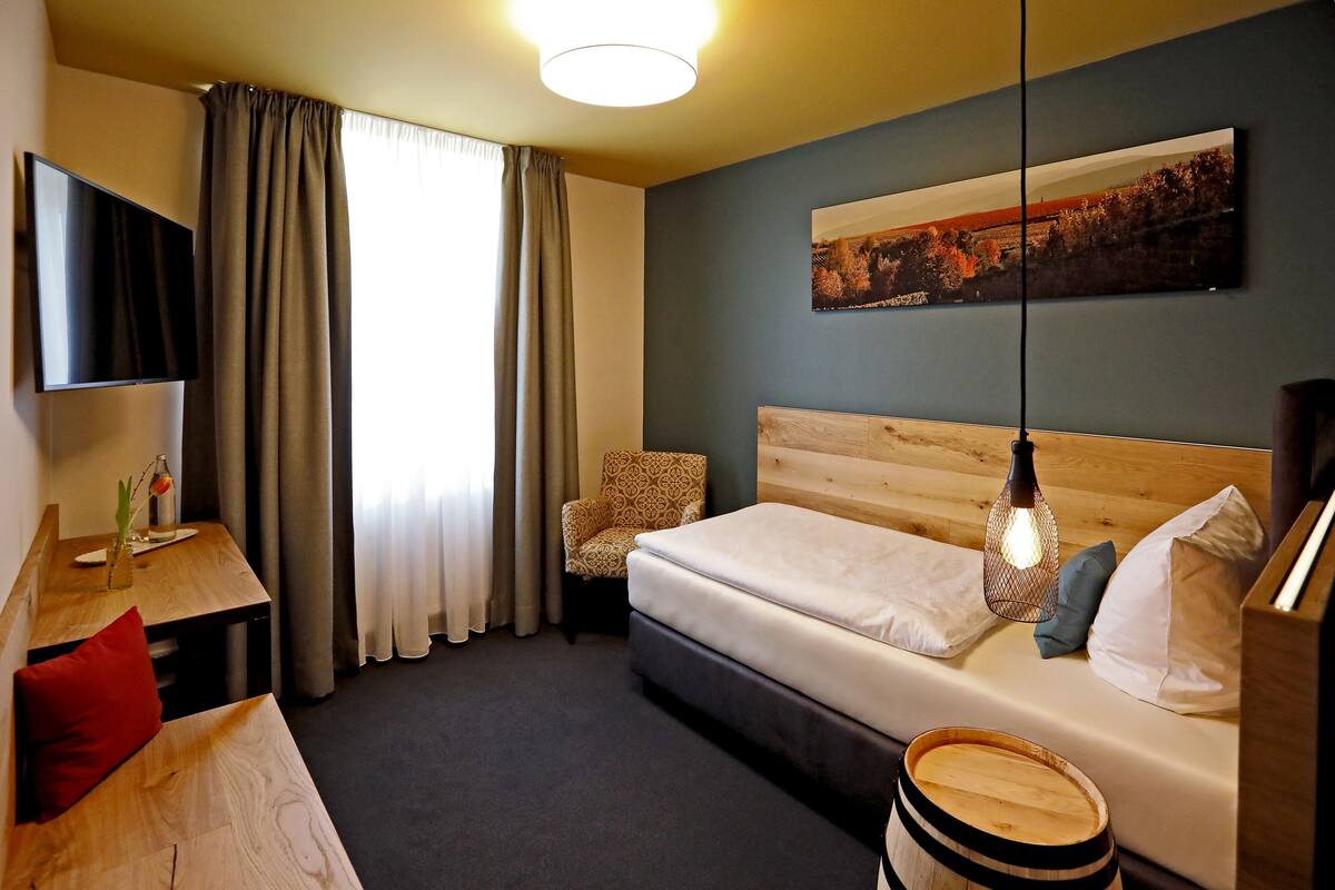 Habitación de hotel con cama, escritorio, silla, televisor y un cuadro en la pared.