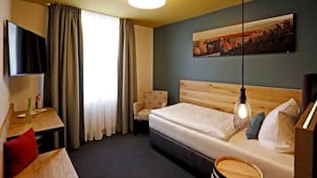 A hotel room with a bed, a desk, a chair, a TV, and a painting on the wall.