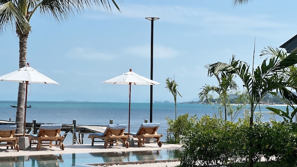 A poolside area with lounge chairs and umbrellas, overlooking a body of water. - Pearl of Samui Resort (Koh Samui)