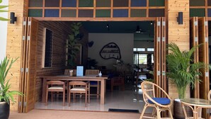 Un interior de fusta amb zona de menjador, cadires, taula i una paret amb prestatgeria.