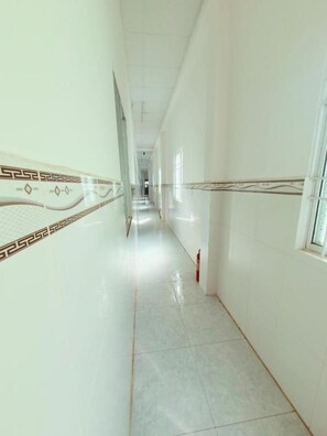 A corridor with a tiled floor and patterned wall design, leading to a door at the end. - Tai Tri Guesthouse (Phu Quoc)