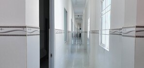 A long, narrow hallway with white walls and patterned borders, leading to a door at the end.