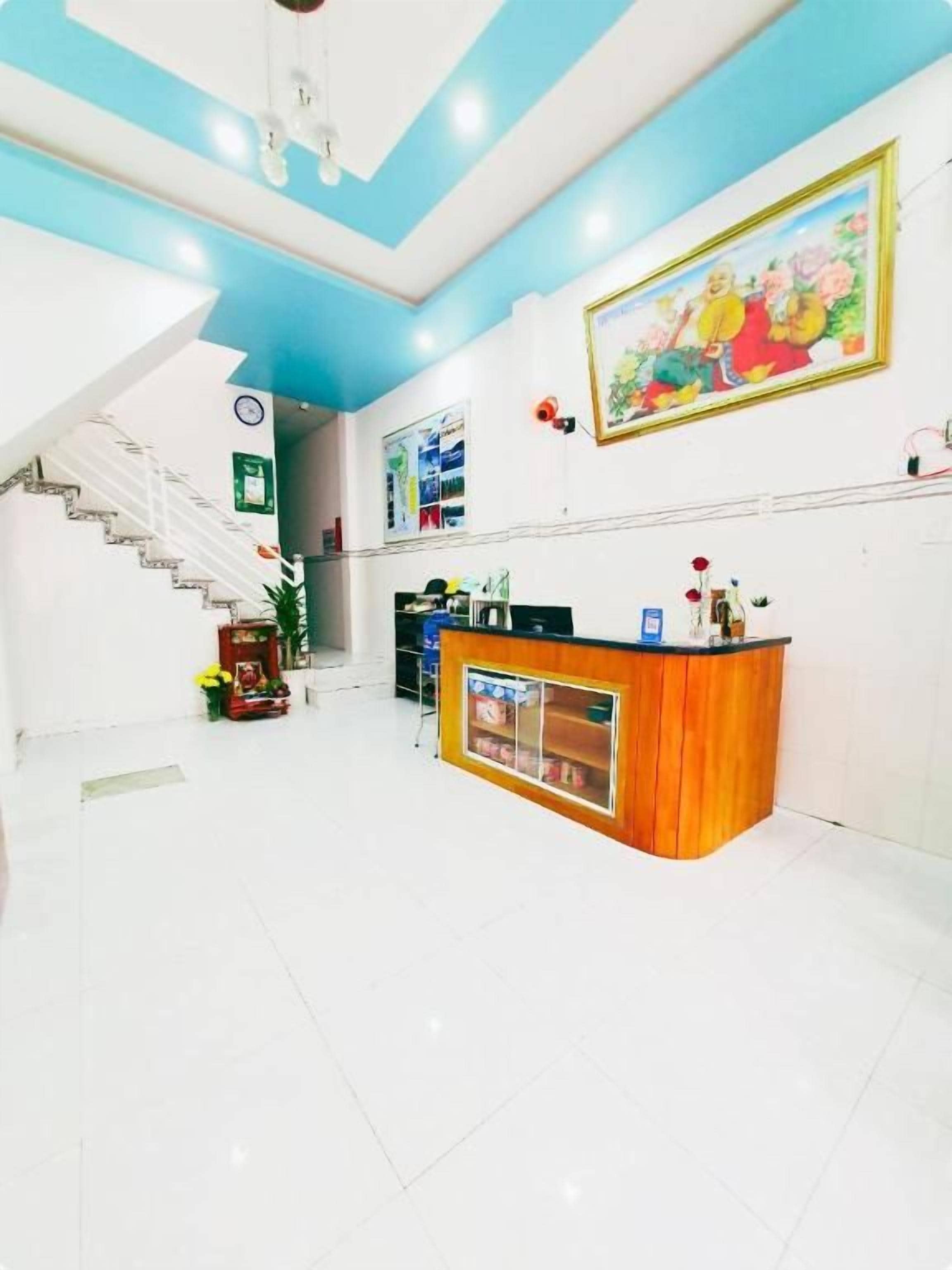 A reception area with a wooden counter, a staircase, and a large painting on the wall.