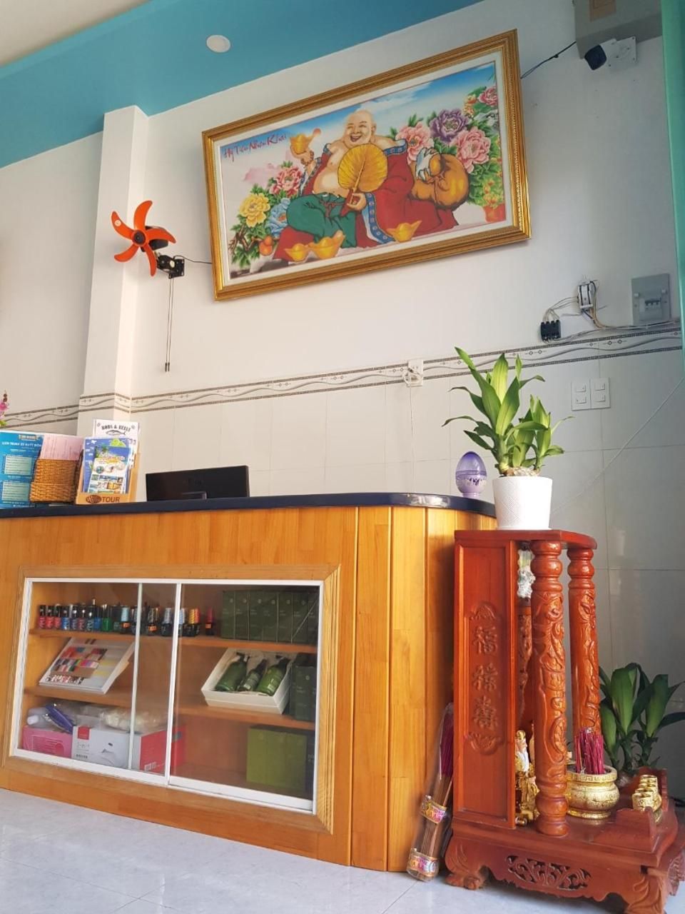 Een receptiebalie met een ingelijste afbeelding erboven, een houten toonbank en een kamerplant.