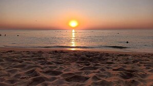 A beach with the sun setting over the horizon, creating a calm and serene atmosphere.