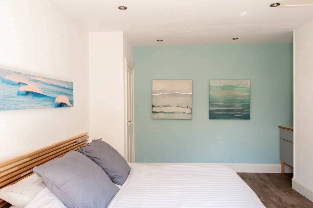 A bedroom with a bed, a wooden headboard, and two wall-mounted paintings.