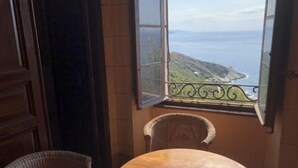 Um quarto com vista para o mar, uma cadeira de vime e uma mesa de madeira.