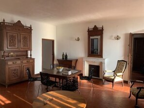 A dining room with a wooden table and chairs, a fireplace, and a large mirror on the wall.