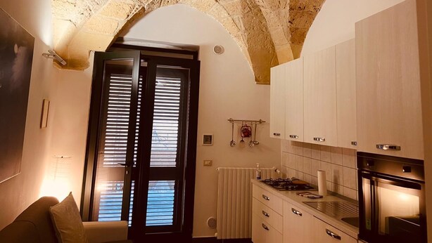 A kitchen with stone ceiling arches, white cabinets, and a built-in oven. - Suite Carlotta Premium (Lecce)