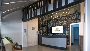 Un espace d’accueil au design moderne, comprenant un comptoir de réception, un coin salon et un mur décoratif orné d’un motif géométrique.