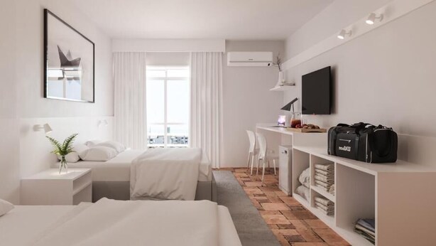 Une chambre d’hôtel moderne équipée d’un lit, d’un bureau, d’une chaise, d’une télévision et d’une armoire.