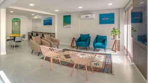 Un salon moderne avec des canapés beige, des fauteuils turquoise et un tapis à motifs.