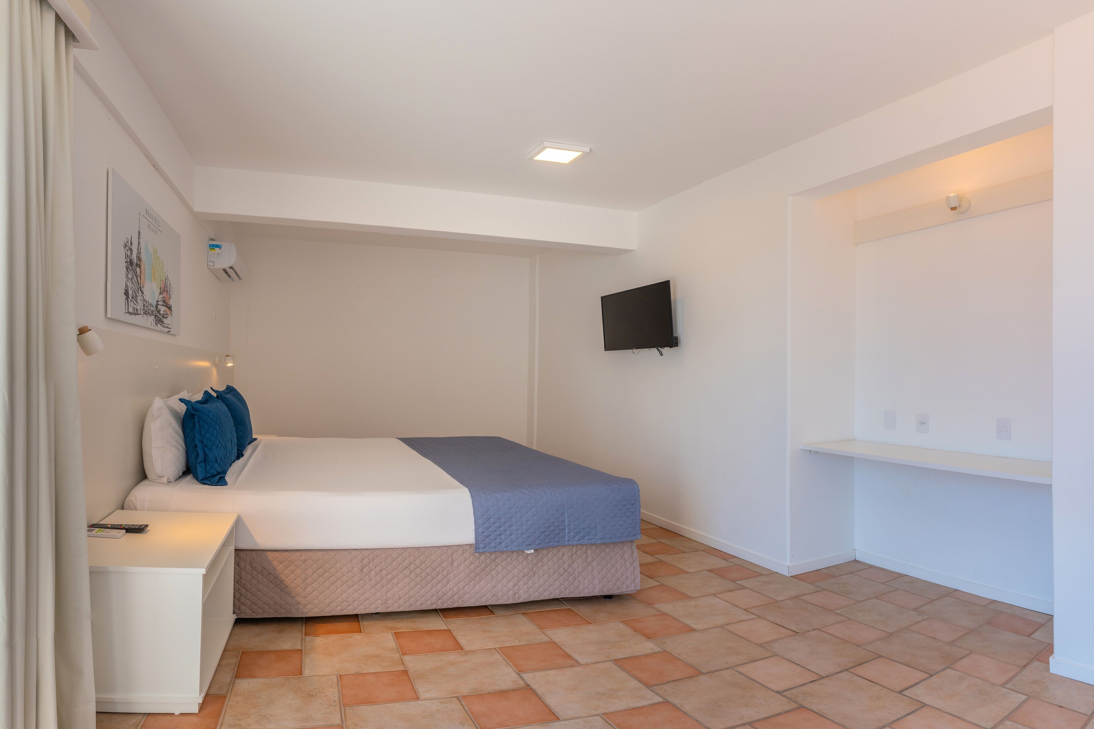Un dormitorio con cama, mesita de noche y televisor de pared.