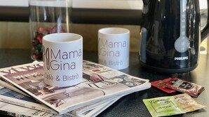 A kitchen counter with two white mugs, a coffee maker, and a stack of magazines. - Hotel Gardenia Fiera (Cermenate)
