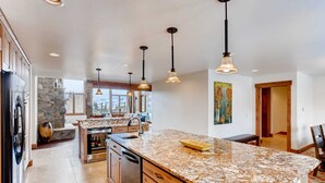 A spacious kitchen with granite countertops, a central island, and pendant lighting.