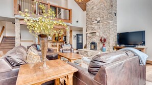 A spacious living area with a stone fireplace, leather sofas, and a large TV.