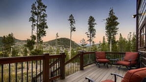 A wooden deck with outdoor furniture and a view of a forested landscape.