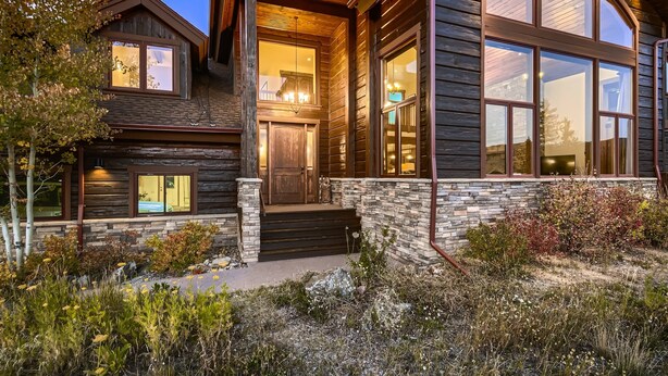 A log cabin with a stone foundation, large windows, and a welcoming entrance.